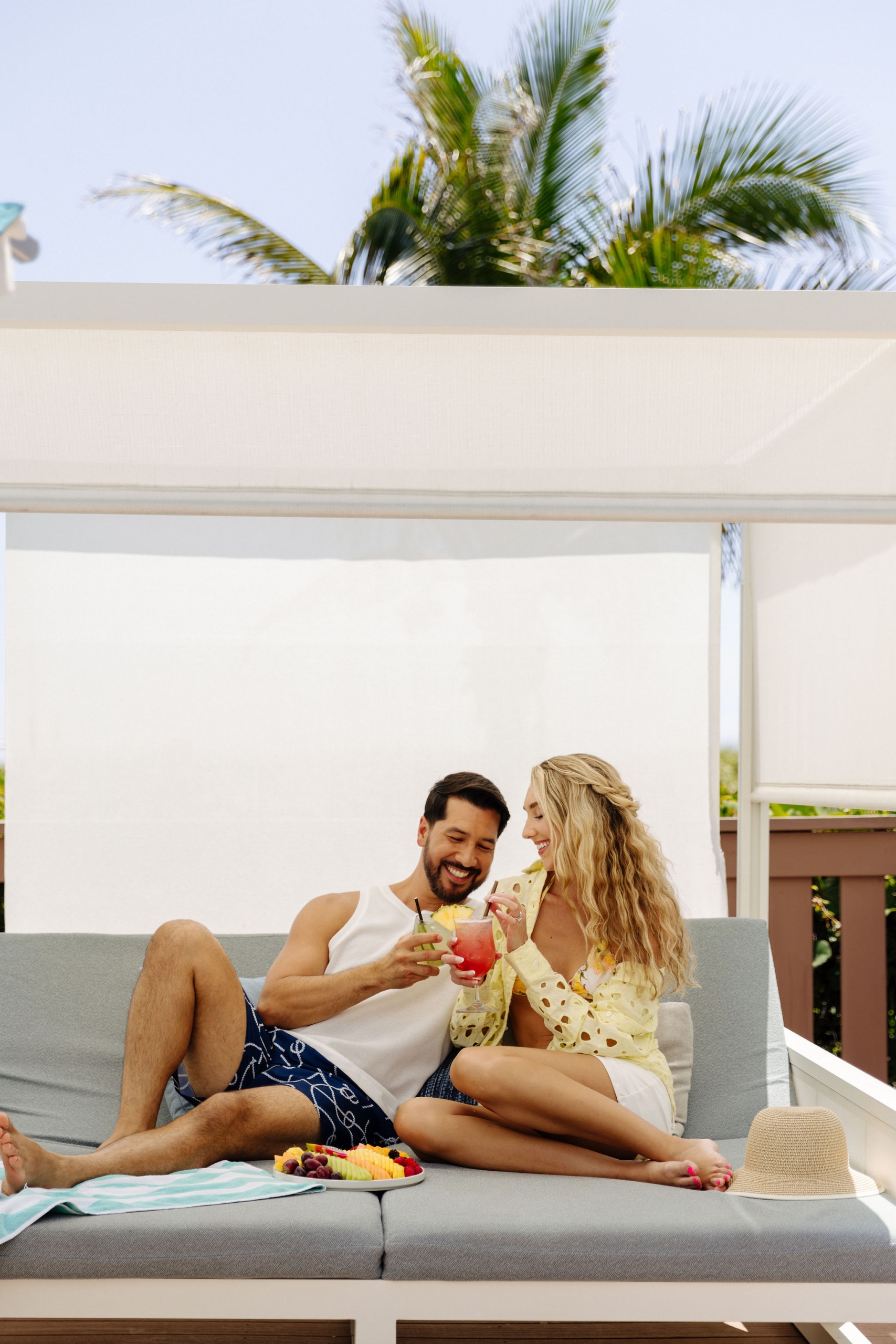 couple eating and drinking in a poolside daybed at the singer oceanfront resort