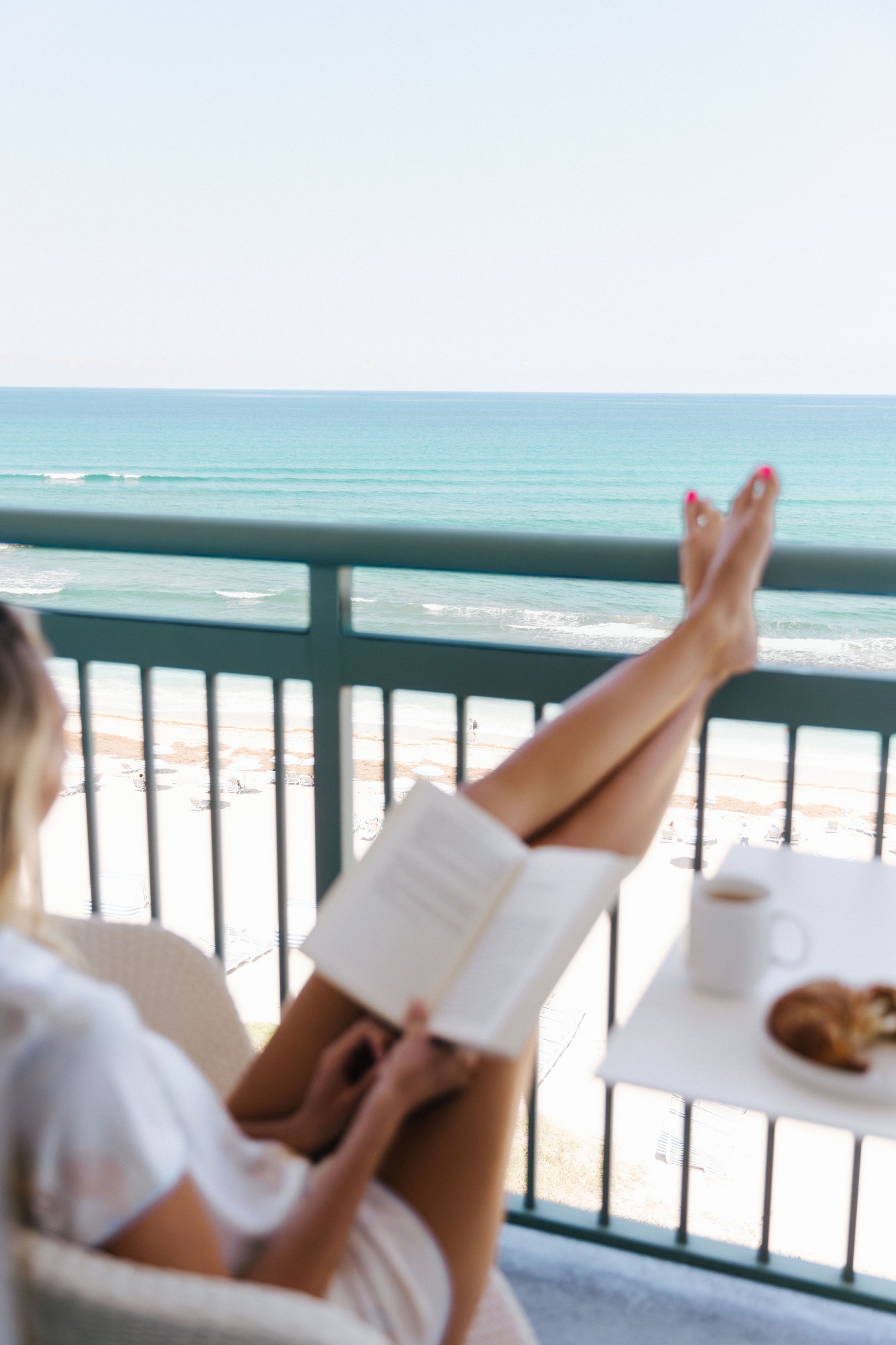 woman reading a book in an oceanfront balcony