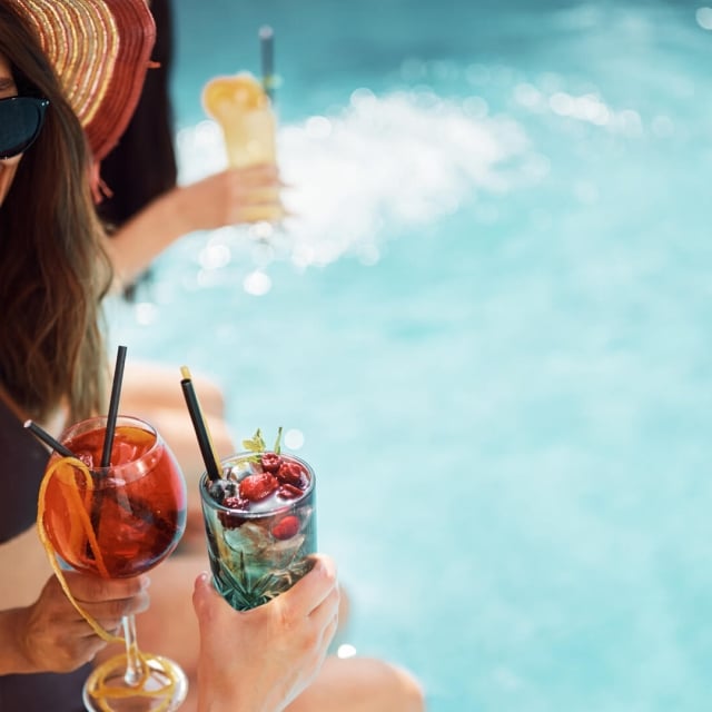 People with cocktail drinks by the pool