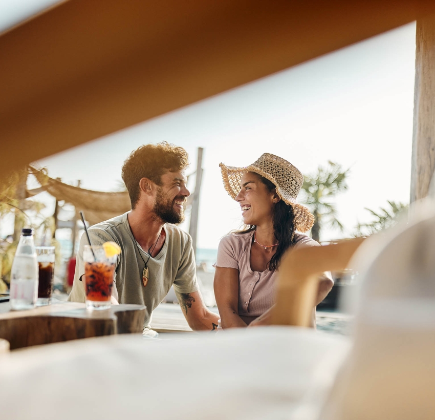 Young happy couple communicating while spending a summer day in a beach café