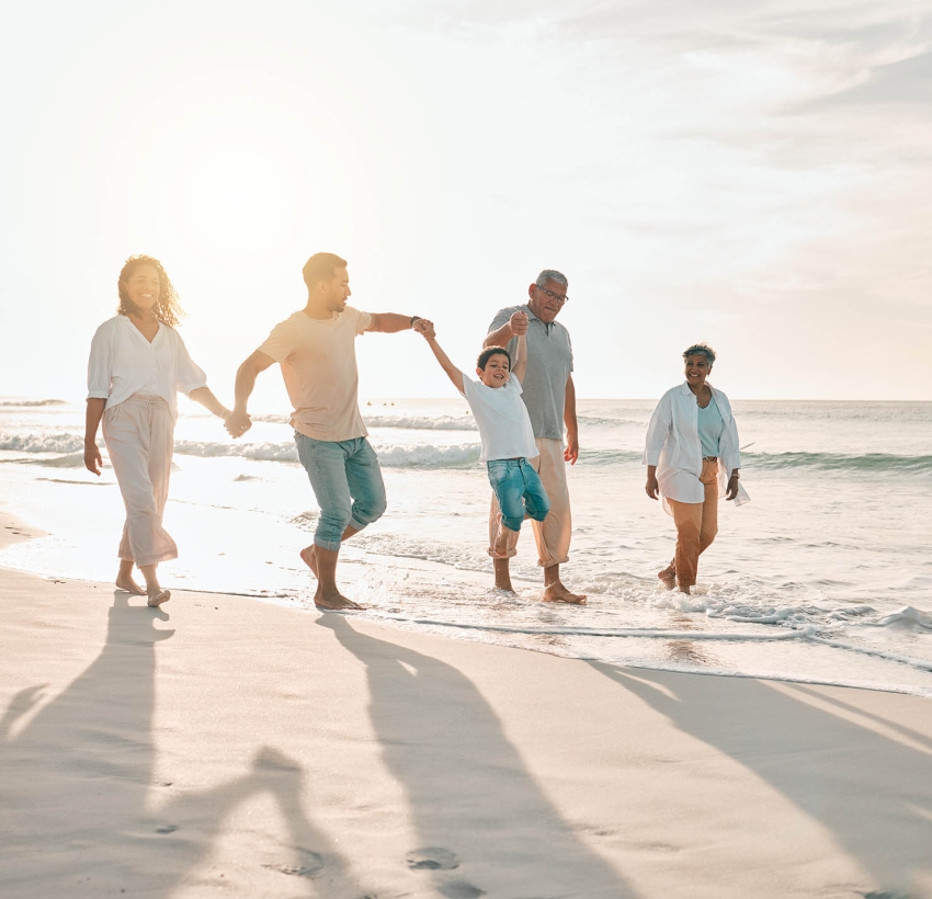 Big family of four at the beach holding hands, swinging their little children