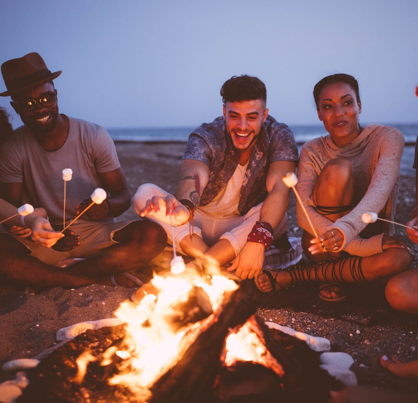 Friends at a bonfire on the beach enjoying at a resort.