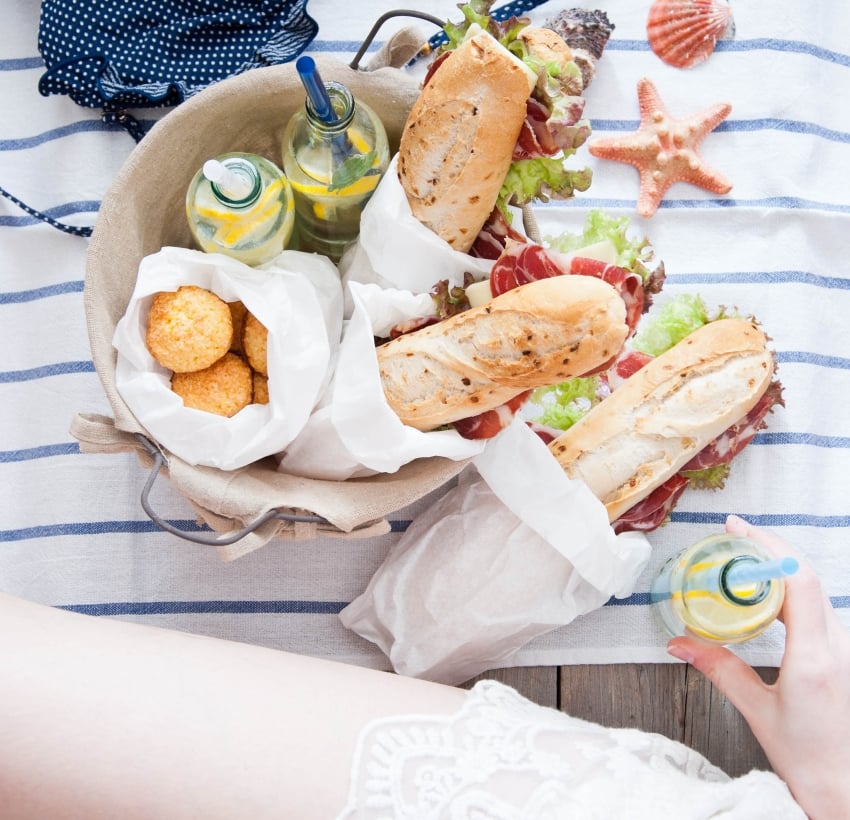 Picnic ham sandwiches and lemonade in a basket in a marine style girl sitting